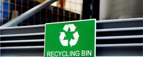 Engraved outdoor signage made of green Gravoply™ engraving material fixed to a recycling container